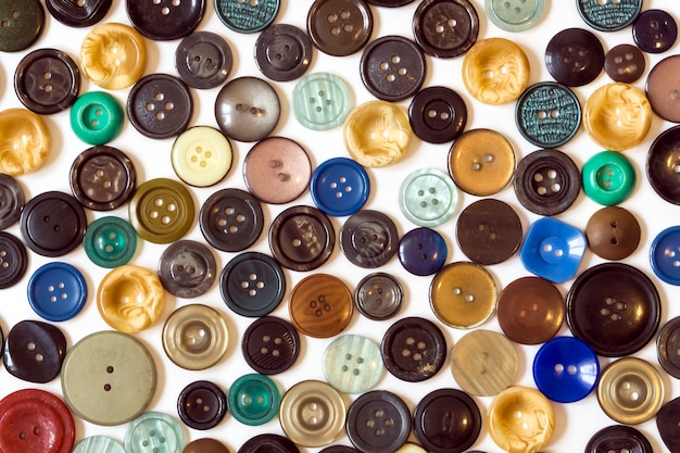 Fondo: botones lisos multicolores dispuestos caóticamente sobre una superficie blanca