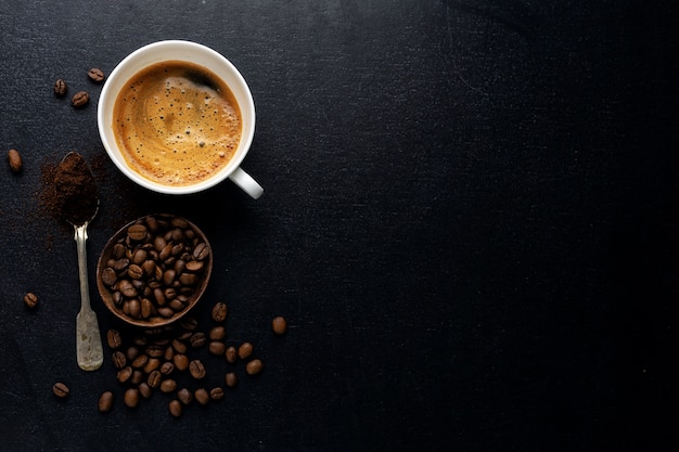 Fondo de café con granos de café, café y cuchara sobre fondo oscuro. Vista desde arriba. Concepto de café.