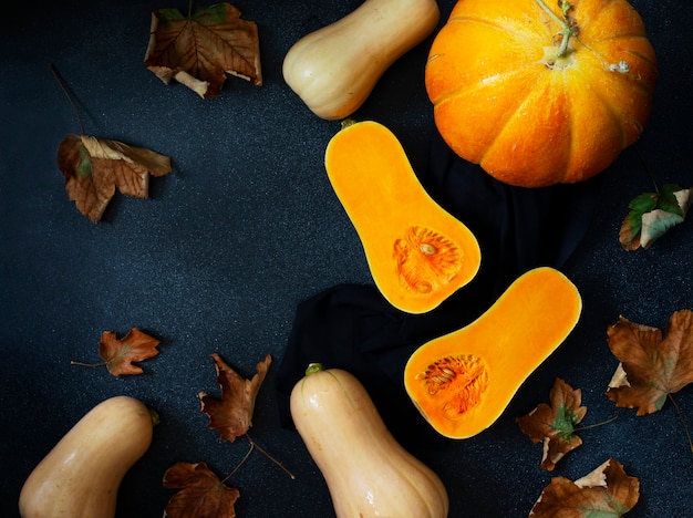 Fondo de calabaza de otoño, varias calabazas y hojas amarillas. Concepto de acción de gracias y Halloween. Bodegón composición plana laico. Fondo negro, vista desde arriba. Espacio para texto.