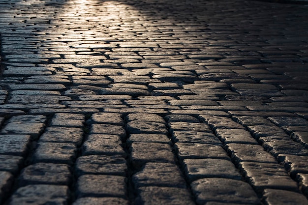 Fondo de camino de piedra adoquinada negra con reflejo de la luz que se ve en la carretera