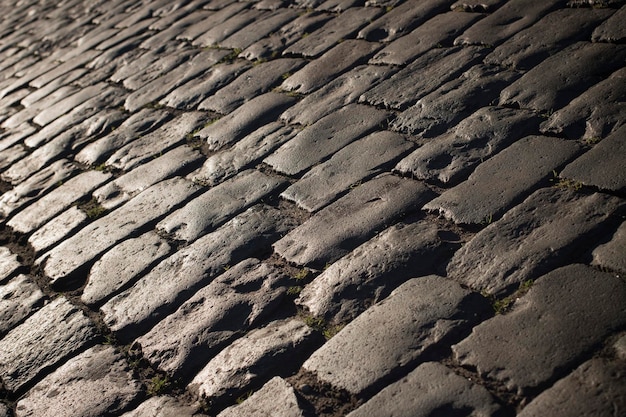 Fondo de camino de piedra adoquinada negra con reflejo de la luz que se ve en la carretera