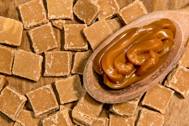 Fondo de caramelos de dulce de leche con cuchara de madera llena de dulce de leche.