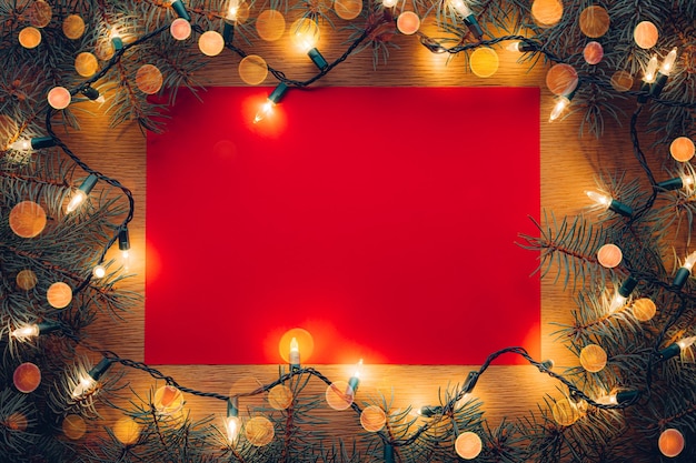 Fondo de carta de papel rojo con ramas de árboles de Navidad y luces de Navidad