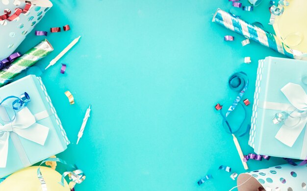 Fondo de celebración con caja de regalo, serpentinas de fiesta coloridas, confeti y sombreros de fiesta de cumpleaños en azul