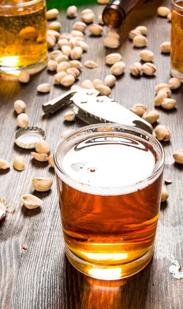 Fondo de cerveza Vaso de cerveza y pistachos en una mesa de madera