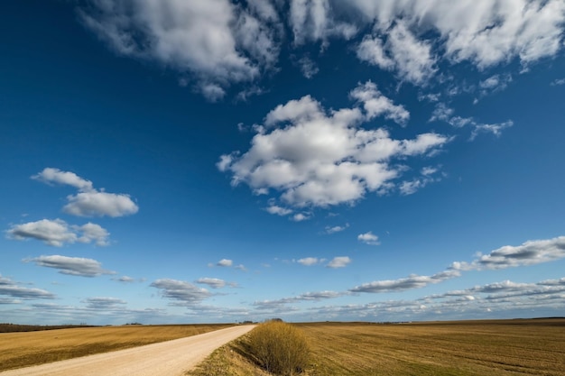 El fondo del cielo azul con grandes nubes de rayas blancas en el campo con el panorama del cielo azul del camino de ripio puede usarse para el reemplazo del cielo