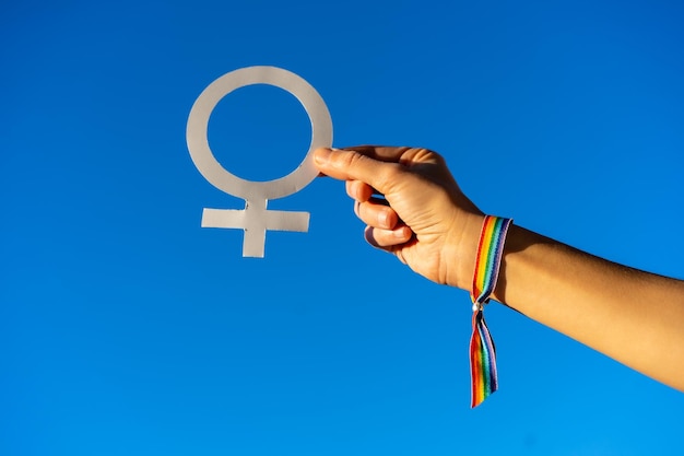 Fondo de cielo azul con una mano de mujer con símbolo femenino a favor del feminismo luchando a favor de la mujer Fuerza femenina Bandera LGTB