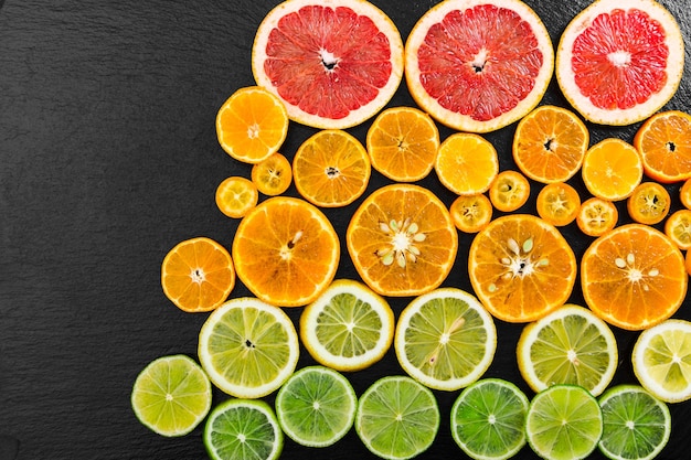 Fondo de cítricos de frutas con pomelo naranja mandarina limón lima y kumquat sobre fondo negro