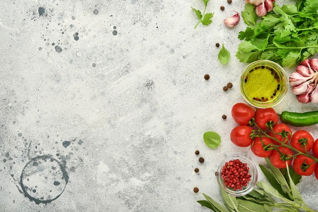 Foto fondo de cocción de alimentos. azafrán fresco, ajo, cilantro, albahaca, tomates cherry, pimientos y aceite de oliva, especias, hierbas y verduras en la mesa de pizarra gris claro. vista superior de los ingredientes alimentarios.