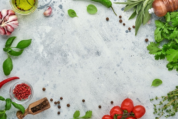 Foto fondo de cocción de alimentos. azafrán fresco, ajo, cilantro, albahaca, tomates cherry, pimientos y aceite de oliva, especias, hierbas y verduras en la mesa de pizarra gris claro. vista superior de los ingredientes alimentarios.