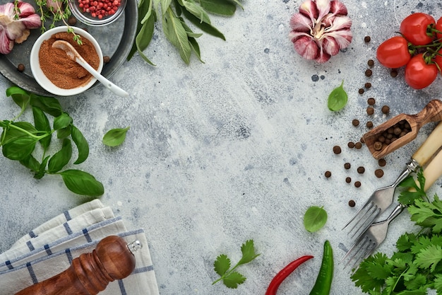 Fondo de cocción de alimentos. Azafrán fresco, ajo, cilantro, albahaca, tomates cherry, pimientos y aceite de oliva, especias, hierbas y verduras en la mesa de pizarra gris claro. Vista superior de los ingredientes alimentarios.