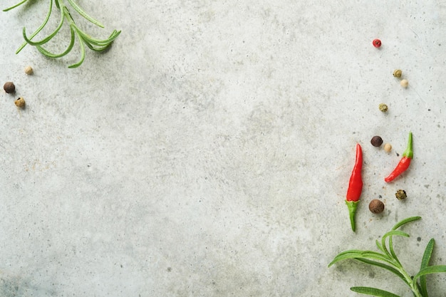 Fondo de cocina de alimentos Ramas de romero verde granos de pimienta y pimientos picantes en la mesa de pizarra gris claro Ingredientes de alimentos vista superior