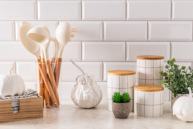 Foto fondo de cocina moderno con elementos de decoración natural calabazas decorativas blancas frascos elegantes para el almacenamiento toalla en una caja de madera