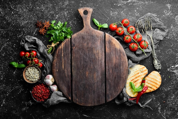 Fondo de cocina de piedra negra. Especias y verduras. Vista superior. Espacio libre para su texto.