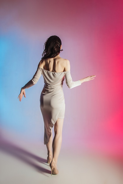 fondo de color, luces de neón, foto de estudio. Retrato de moda de una joven morena elegante.