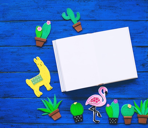 Foto fondo colorido creativo con elementos dibujados y cortados a mano de moda llama o cactus lama flamenco rosa y libro en blanco para texto conjunto hecho a mano exótico tropical en la vista superior de la mesa de textura azul