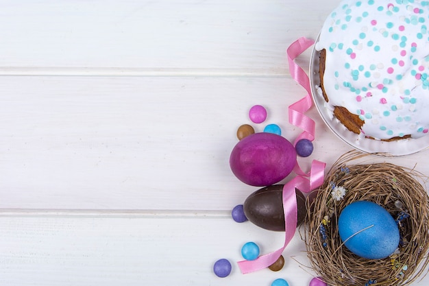Fondo colorido con huevos de Pascua sobre fondo de tablero de madera blanca.