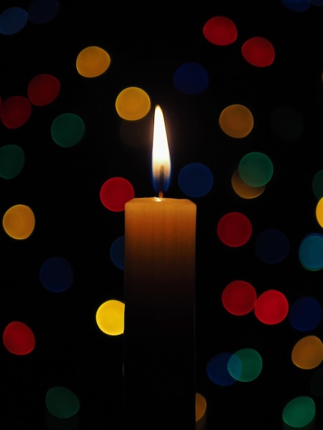 Fondo colorido Primer plano de velas encendidas y bokeh multicolor sobre un fondo negro