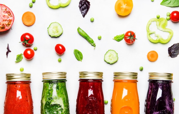 Fondo de comida y bebida Coloridos jugos y batidos de vegetales veganos en botellas en la vista superior de fondo blanco