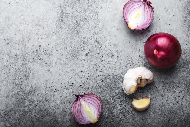 Fondo de comida con espacio libre para texto. Primer plano, vista superior de cebollas frescas crudas cortadas y ajo sobre fondo de piedra gris rústico, cocina, comida vegetariana o concepto de alimentación saludable