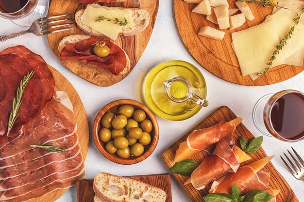 Fondo de comida italiana con jamón, queso, aceitunas, pan y vino