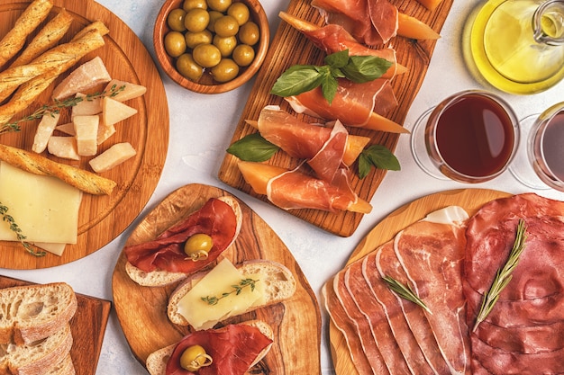 Fondo de comida italiana con jamón, queso, aceitunas, pan y vino