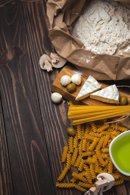 Foto fondo de comida italiana con mozzarella de pasta espiral de espagueti y aceitunas de queso camembert y harina de aceite de oliva juego de pasta