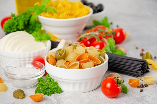 Fondo de comida italiana con pasta cruda tomates frescos albahaca espaguetis aceitunas mozzarellaa