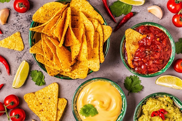 Fondo de comida mexicana: guacamole, salsa, salsas de queso con nachos, vista superior.