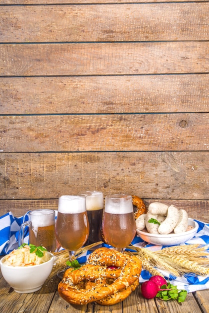 Fondo de comida Oktoberfest, menú de comida tradicional de vacaciones bávaras, salchichas con pretzels, chucrut, vaso de cerveza y tazas en el espacio de copia de fondo iluminado por el sol de madera