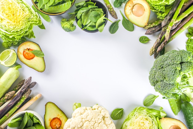 Fondo de comida de primavera de dieta saludable. Surtido de vegetales verdes orgánicos crudos frescos: brócoli, coliflor, calabacín, pepinos, espárragos, espinacas, aguacate, repollo en fondo blanco