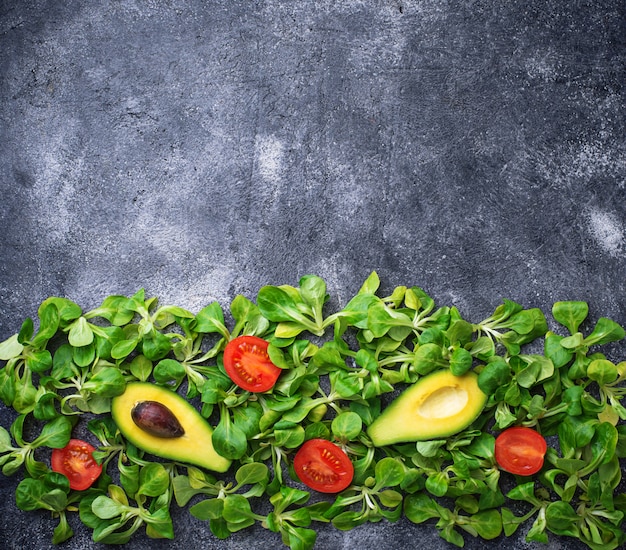 Fondo de comida verde con maíz, lechuga, tomate y aguacate.