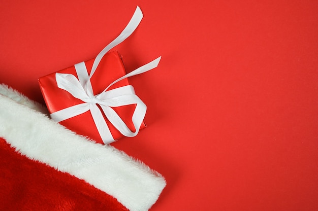 Foto fondo de compras navideñas con gorro de santa y caja de regalo roja con ribbn