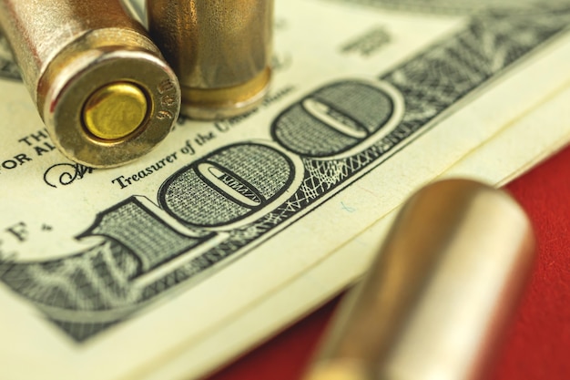 Fondo de concepto de comercio ilegal de munición con balas y dinero, primer plano de billete de cien dólares de EE. UU.