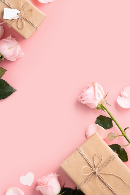 Fondo de concepto de diseño del día de San Valentín con flor de rosa rosa y caja de regalo kraft envuelta sobre fondo de mesa rosa