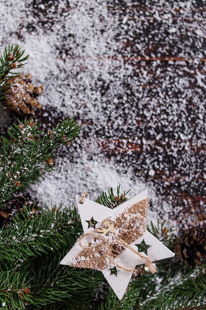 Fondo de concepto de Navidad, decoración de estrellas hechas a mano y verdes árboles de Navidad en una mesa de madera, salpicada de nieve blanca