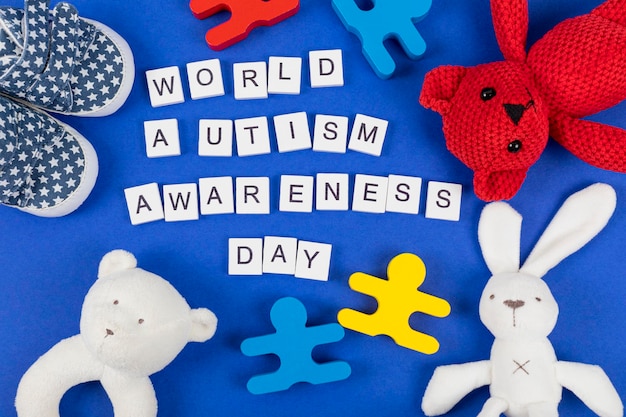 Fondo de concienciación sobre el autismo Juguetes para bebés con la inscripción Día Mundial de la Concienciación sobre el Autismo en fondo azul