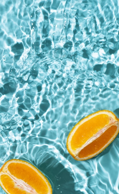 Fondo creativo de verano con rodajas de naranja en el agua de la piscina