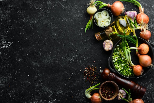 Fondo culinario Cebollas ajo y especias sobre un fondo de piedra negra Vista superior