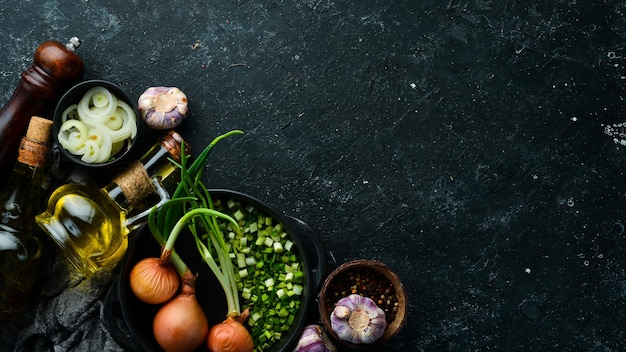 Fondo culinario Cebollas ajo y especias sobre un fondo de piedra negra Vista superior