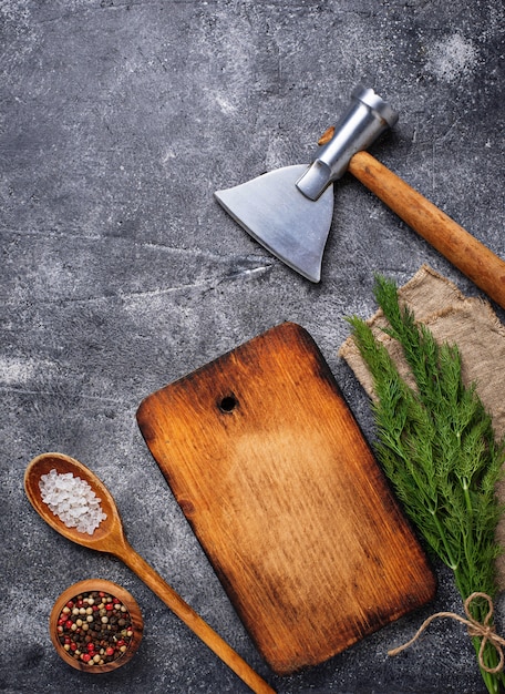 Fondo culinario con especias, tabla de cortar y hacha.