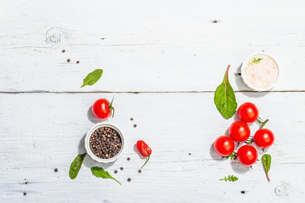 Fondo culinario moderno con tomates cereza especias y hierbas tablas de madera blanca