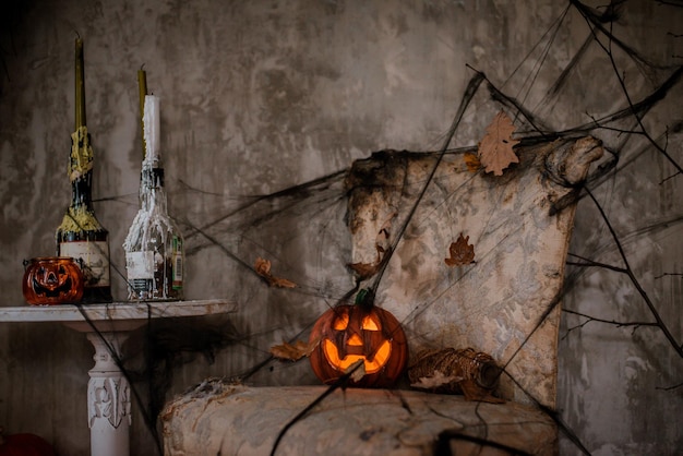 Fondo de decoraciones para la celebración de Halloween Una composición aterradora con la calabaza de Jack y velas encendidas, telarañas y una escoba de bruja en una pared de hormigón