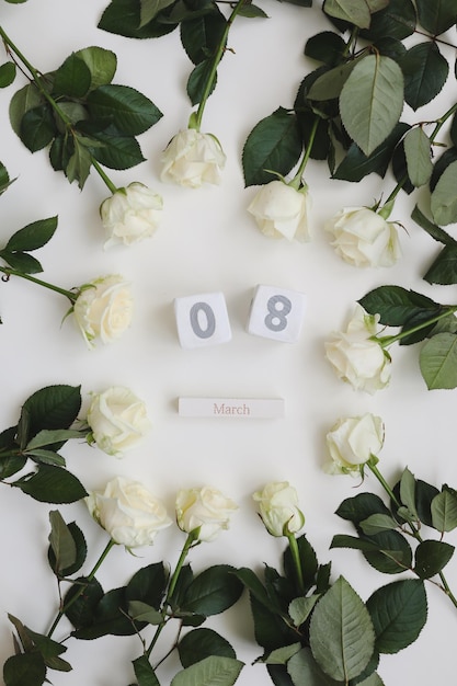 Fondo del Día de la Mujer del 8 de marzo con rosas blancas y lugar para el texto en la vista superior de fondo blanco