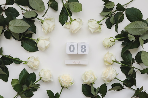 Fondo del Día de la Mujer del 8 de marzo con rosas blancas y lugar para el texto en la vista superior de fondo blanco