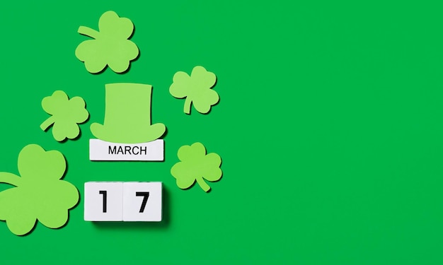 Fondo del día de San Patricio Calendario de madera con tréboles y sombrero de duende sobre fondo verde