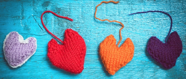 Fondo del día de San Valentín. Corazones tejidos multicolores se encuentran en los viejos tableros azules.