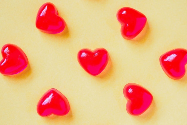 Foto fondo del día de san valentín con dulces en forma de corazón rojo sobre fondo amarillo