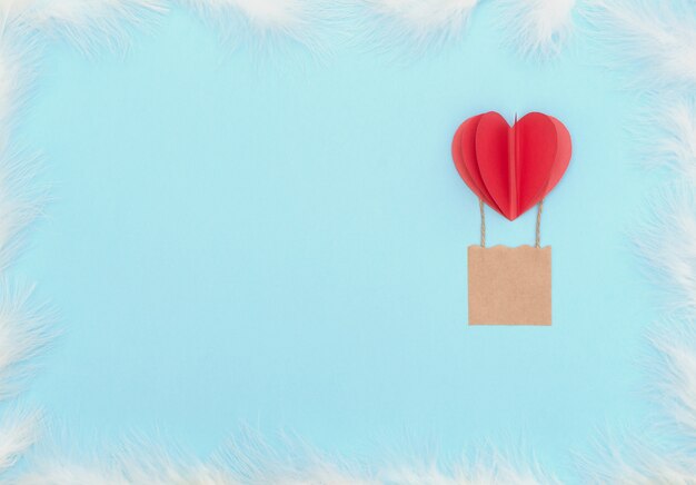 Fondo del día de San Valentín con globo de corazón rojo con canasta y plumas blancas