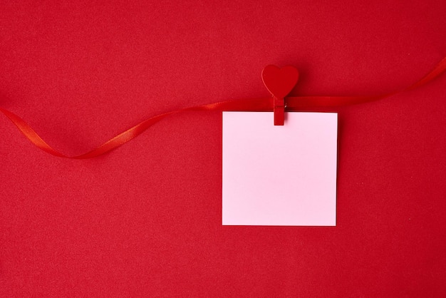 Fondo de día de San Valentín hoja de papel vacía con cinta festiva en el fondo rojo